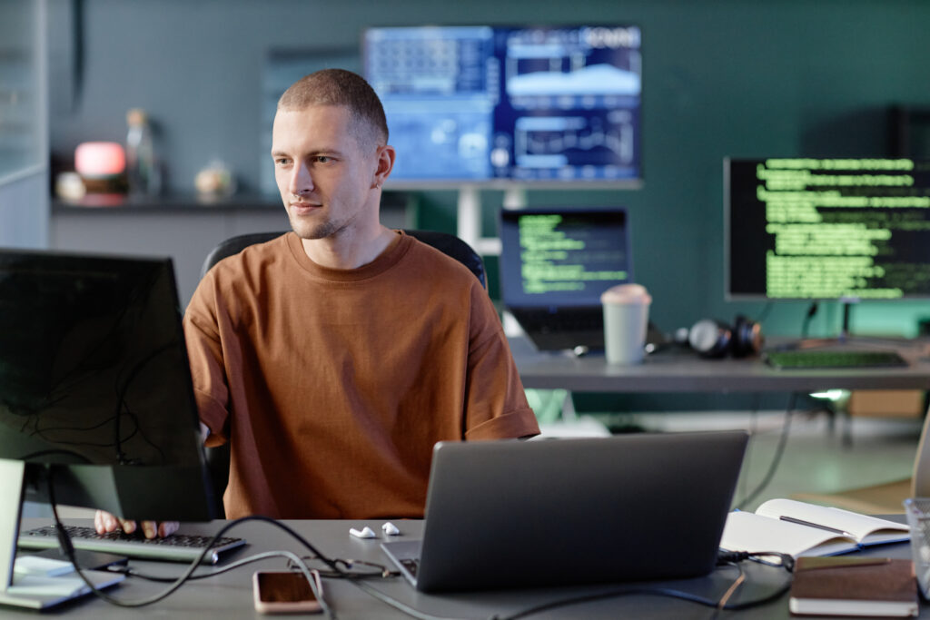 calm male programmer coding computer working alone desk with laptop office