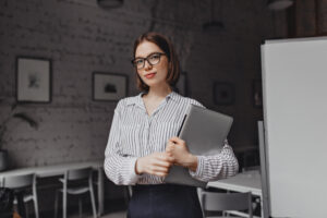 portrait brown eyed business woman black white outfit stylish glasses posing with laptop white room