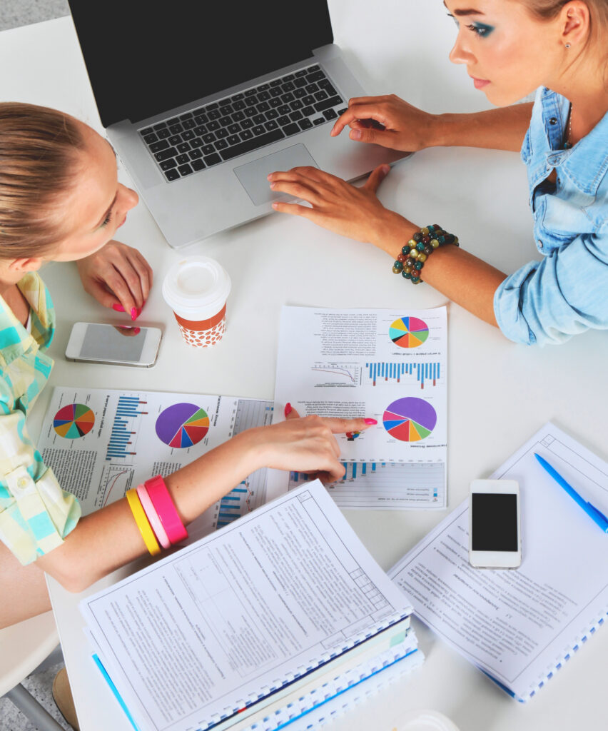 two women working together office sitting desk